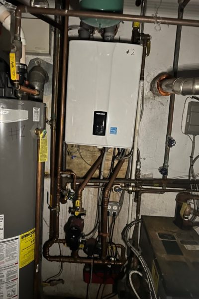 A gas water heater and some pipes in a room.