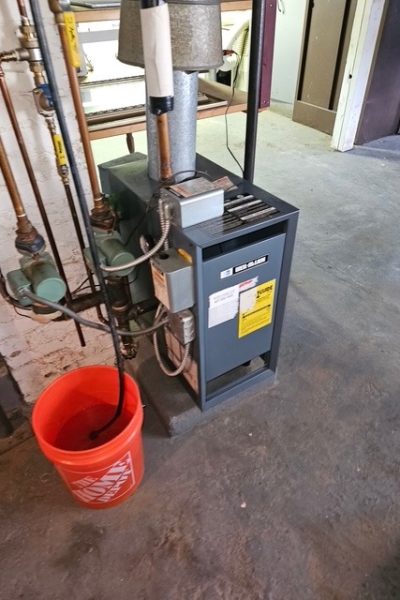 Basement boiler with pipes and orange bucket