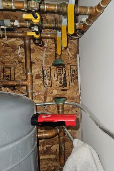 Copper plumbing pipes with valves and red tool