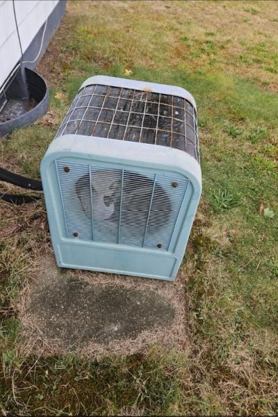 Old outdoor AC condenser unit on grass