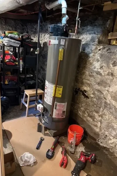 A water heater sitting in the corner of a room.