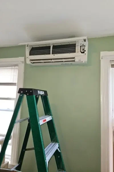 Green ladder beneath wall-mounted split air conditioner
