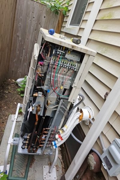 Open outdoor HVAC unit with exposed wiring